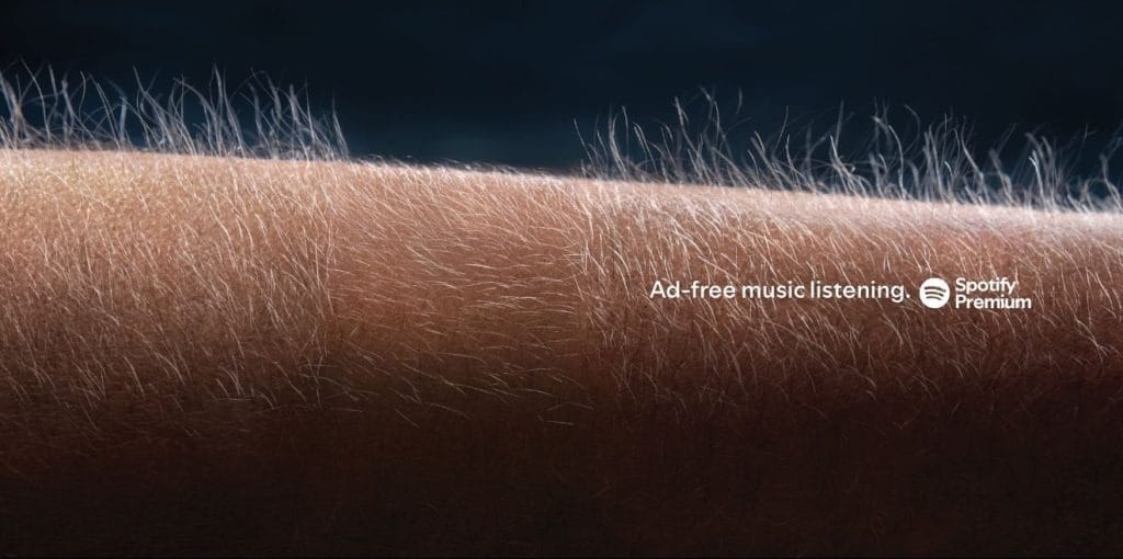 Forearm close-up with an ad promoting Spotify Premium: 'Ad-free music listening' text on the skin.