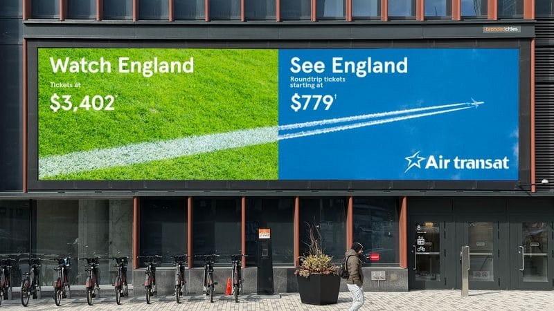 Image » new classic Two-panel outdoor billboard advertising England trips: 'Watch England' with tickets at ,402 and 'See England' from 9 by Air Transat, on a green/blue backdrop.